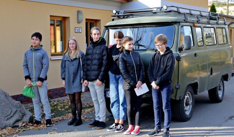 Ein alter ausrangierter Militärbulli, davor mehrere Jugendliche.
