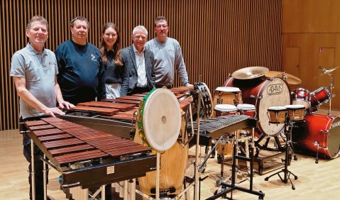 Fünf Menschen stehen hinter mehreren Marimbas, Bongos, Congas und allerlei anderen Percussion-Instrumenten.