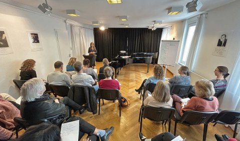 Ein kleiner Saal mit einem Flügel an dessen Ende.