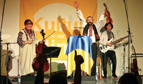 Ein kleines Ensemble in wei&szlig;en Oberteilen und schwarzen Hosen auf einer kleinen B&uuml;hne.