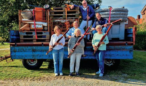 F&uuml;nf Fagottist:innen auf und vor einem alten Anh&auml;nger auf Spiekeroog. Mit ihren Fagotten in den H&auml;nden.