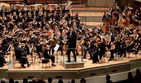Ein Sinfonieorchester aus jungen Musiker:innen auf der mit Parkett ausgelegten Bühne des Berliner Philharmonie.