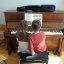 Zwei Kinder die sich eine Klavierbank teilen und an der Klaviatur spielen.