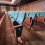 Theaterstuhlreihen aus Holz mit Tannengrün-blauen Polstern in einem rechtwinkligen Saal.