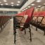 Orange-rot bespanntes, schlichtes Theatermobiliar. Decke und Wände wirken wie ältere Mehrzweckhalle.